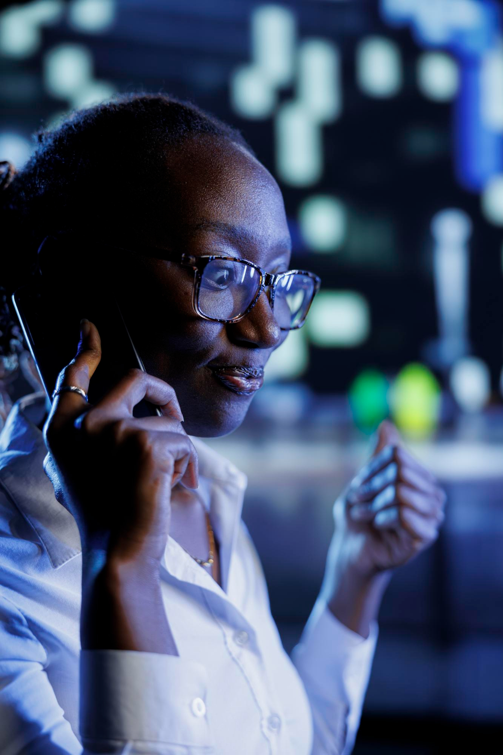 A support agent speaking on a call in a low-lit operations room, screens behind her.
