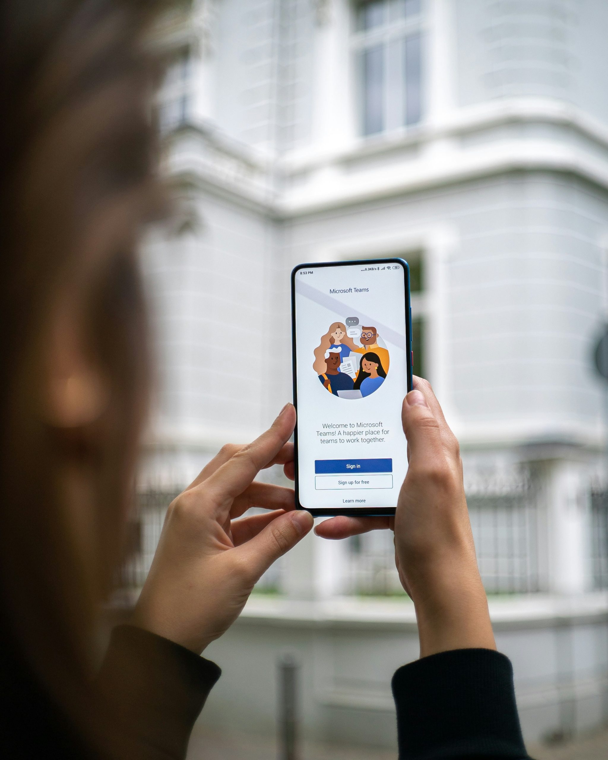 A person holding a phone showing the Microsoft Teams app.